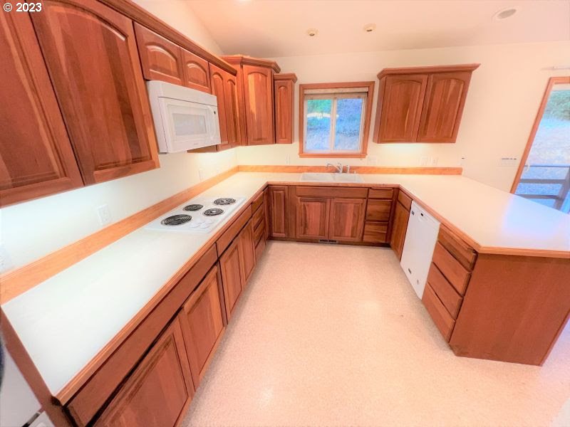 92831 Walluski Loop Astoria, OR 97103 - Photo 21 of 32 a kitchen with stainless steel appliances a sink a stove top oven a refrigerator and dishwasher