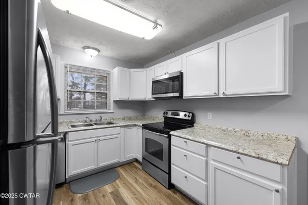 a kitchen with stainless steel appliances granite countertop a stove a sink and a microwave