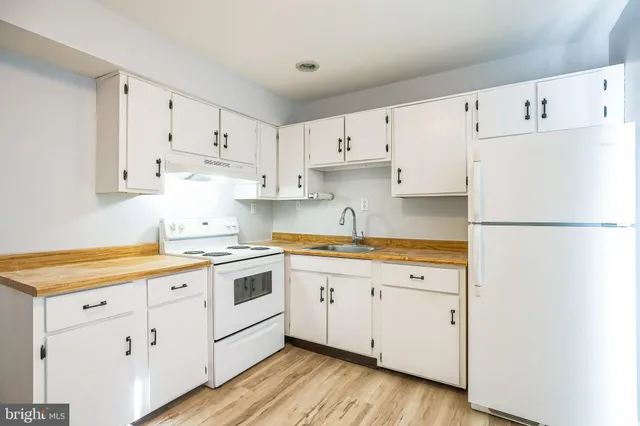 a kitchen with cabinets appliances wooden floor and a window