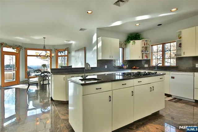 a large kitchen with granite countertop a large window and white stainless steel appliances