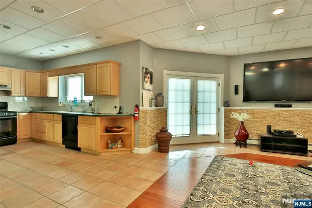 a living room with stainless steel appliances furniture and a flat screen tv