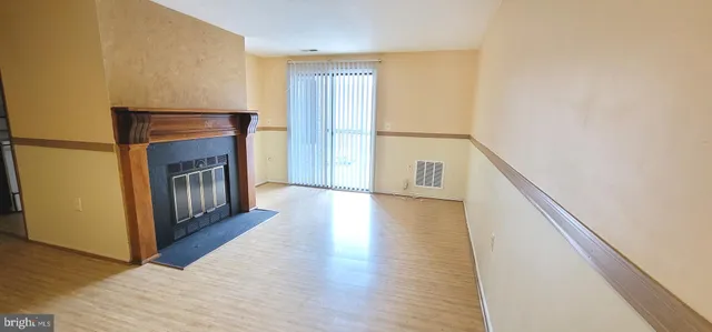 a hallway with wooden floor fireplace and windows