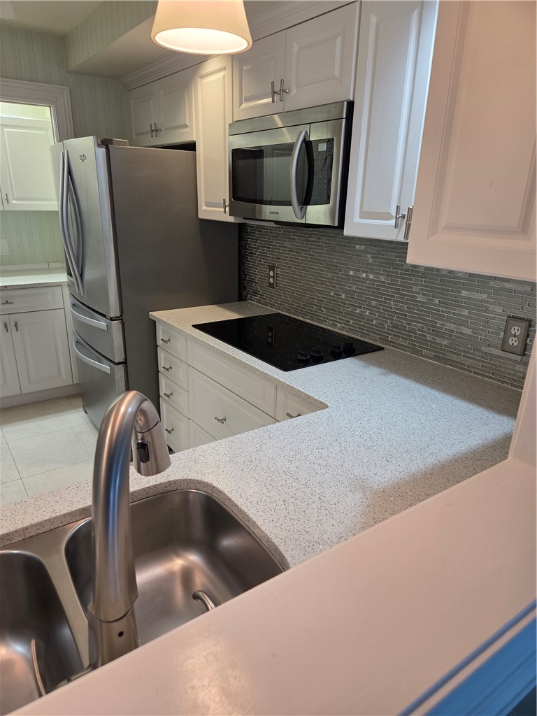 1903 Bay Road, Unit 206 Vero Beach, FL 32963 - Photo 23 of 30 a kitchen with stainless steel appliances a sink a stove a microwave a refrigerator and cabinets