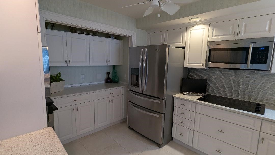 1903 Bay Road, Unit 206 Vero Beach, FL 32963 - Photo 8 of 30 a kitchen with stainless steel appliances white cabinets and a refrigerator