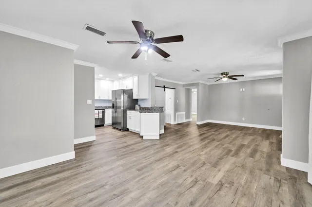 a view of empty room with wooden floor and ceiling fan