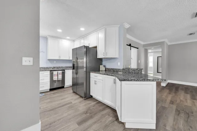 a kitchen with granite countertop a refrigerator and a stove top oven