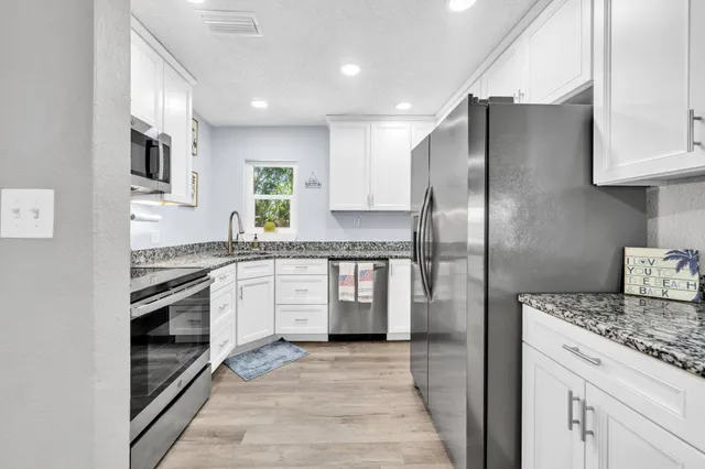 a kitchen with stainless steel appliances granite countertop a refrigerator a stove and a sink