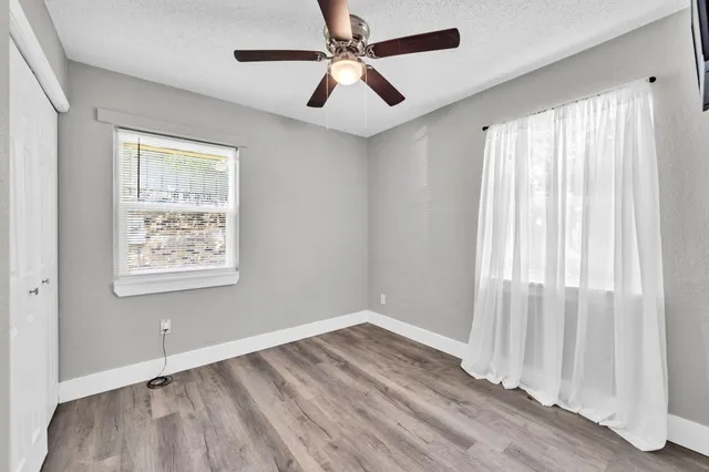 a view of an empty room and window a ceiling fan