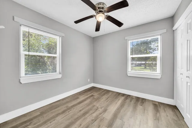 a view of an empty room with wooden floor and a window