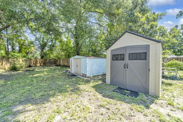 a backyard of a house with a large tree and wooden fence