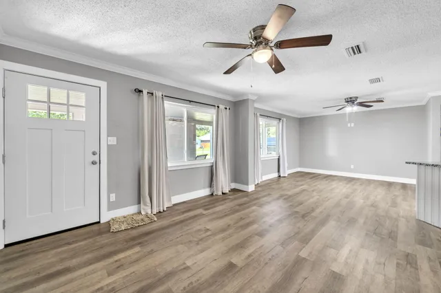 a view of empty room with wooden floor and fan
