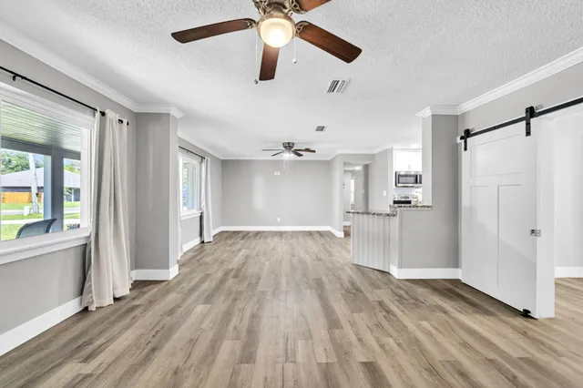 a view of empty room with wooden floor and fan