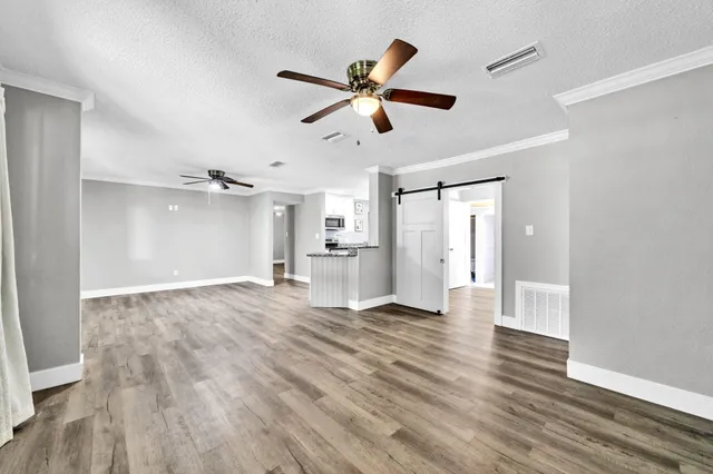 a view of empty room with wooden floor and ceiling fan
