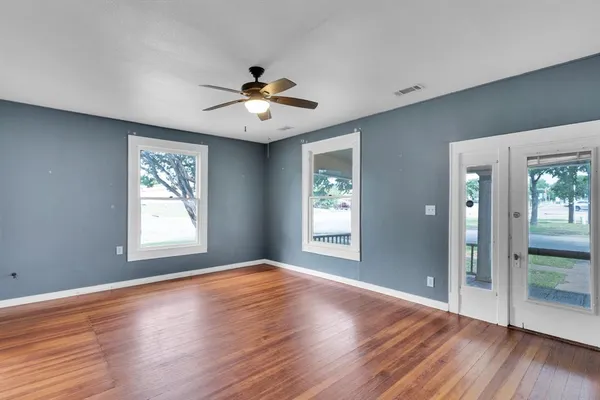a view of an empty room with wooden floor and a window