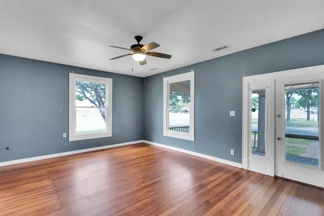 a view of an empty room with wooden floor and a window