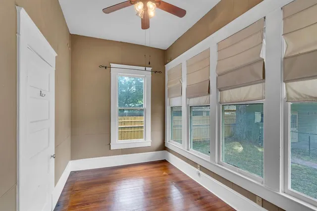 a view of an empty room with a window and wooden floor