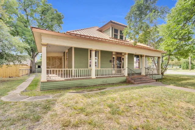 a view of a house with a yard and large tree