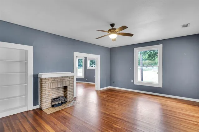 a view of an empty room with a window and wooden floor