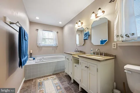 a spacious bathroom with a double vanity sink mirror and bathtub