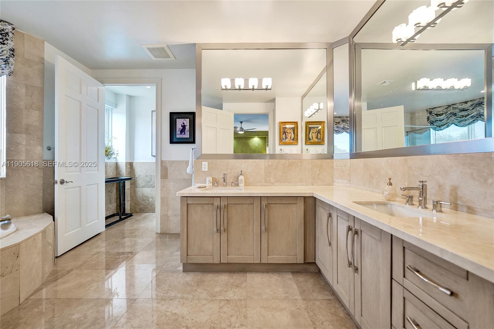 516 Hendricks Isle, Unit 2C Fort Lauderdale, FL 33301 - Photo 40 of 77 a spacious bathroom with a double vanity sink a mirror and a bathtub