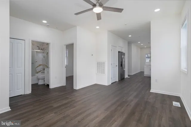 an empty room with wooden floor and a ceiling fan