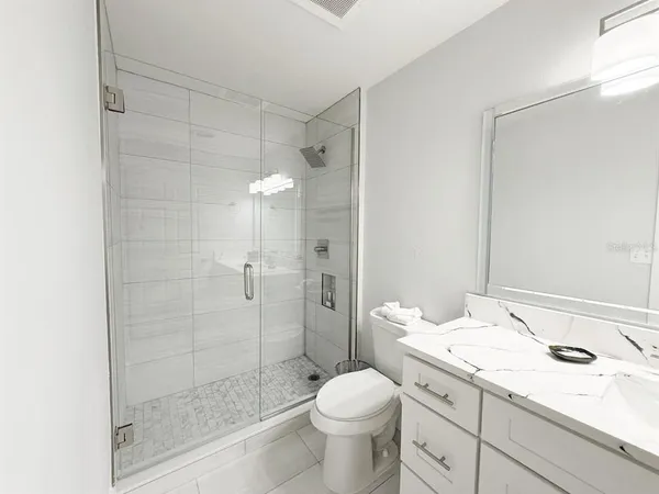 a bathroom with a granite countertop sink a toilet and shower