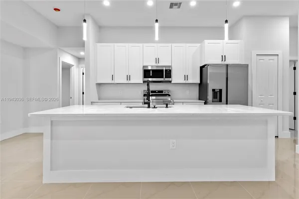 a kitchen with stainless steel appliances a sink a refrigerator and a refrigerator