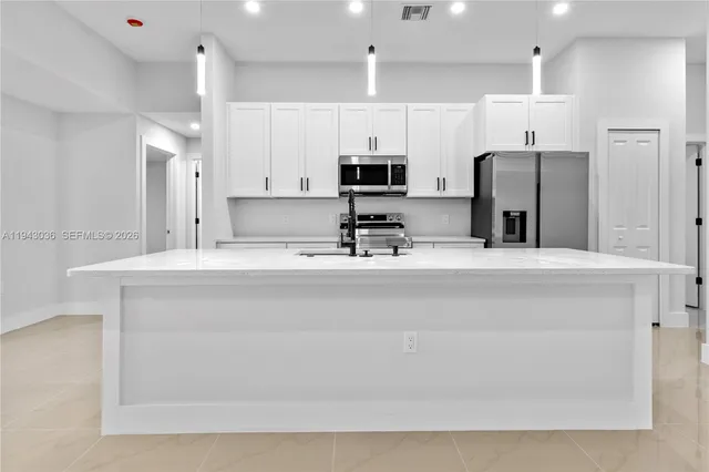 a kitchen with stainless steel appliances a sink a refrigerator and a refrigerator