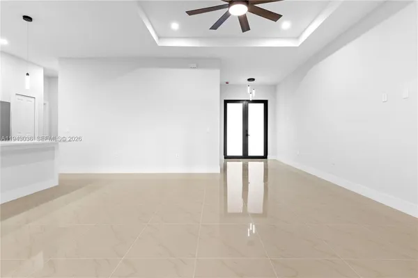 an empty room with chandelier fan and windows