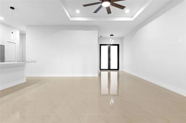 an empty room with chandelier fan and windows