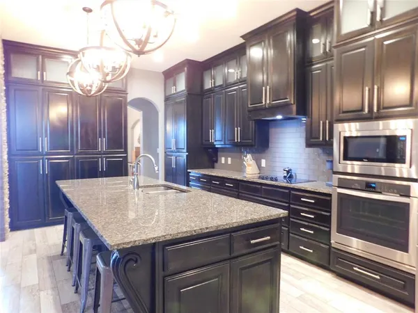 a kitchen with stainless steel appliances granite countertop a sink dishwasher and a stove with wooden floor