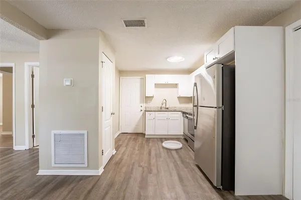 a view of a kitchen with a refrigerator and wooden floor