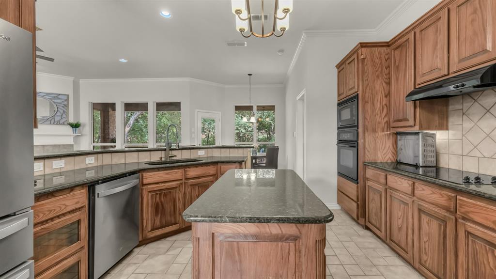 203 Mockingbird Lane Aledo, TX 76008 - Photo 19 of 37 Kitchen featuring a central island, wood cabinetry, dark countertops, built-in double ovens, and tile flooring