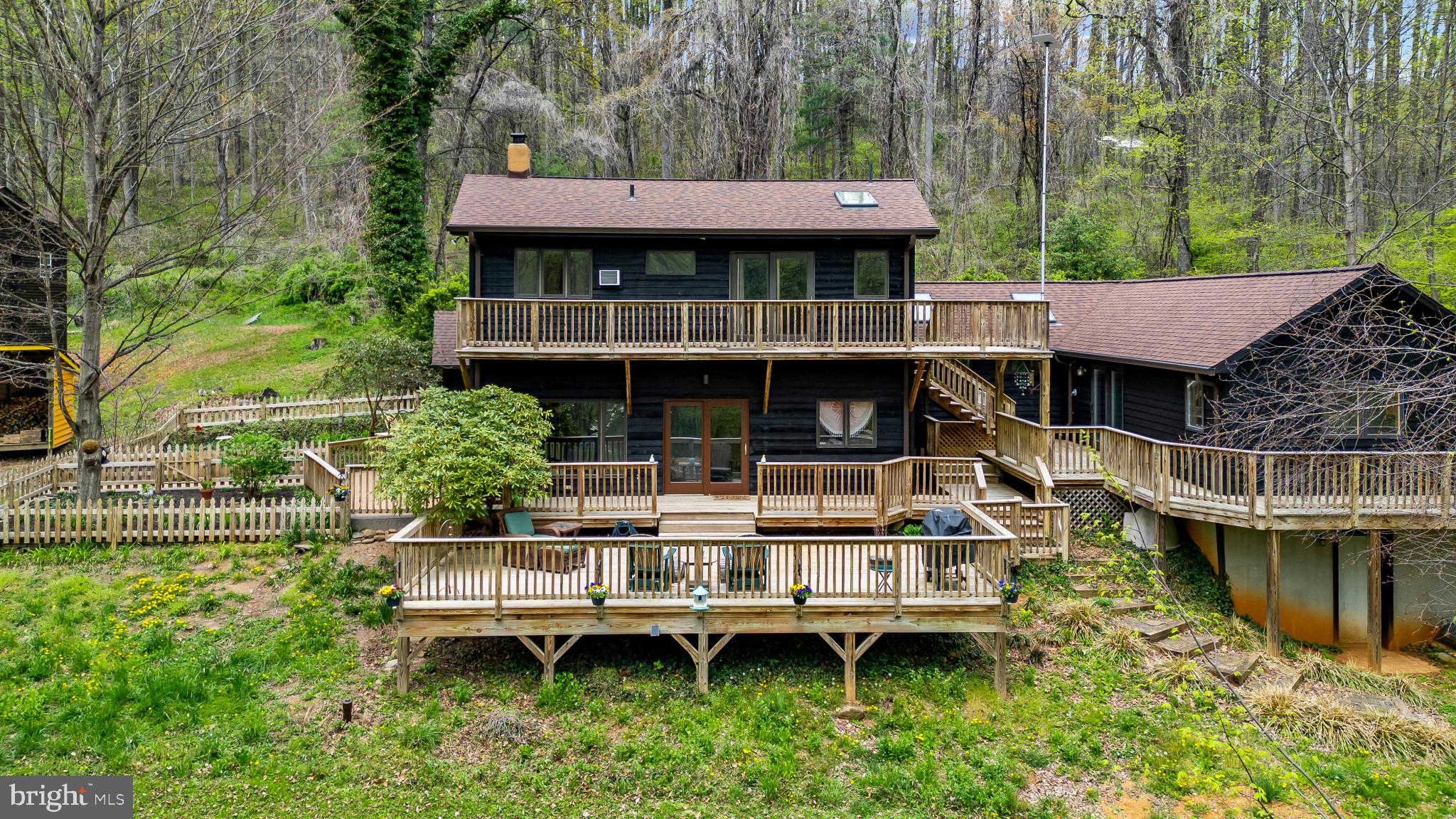 a view of a house with a wooden deck and a yard with a large tree