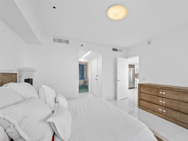 a spacious bedroom with a bed and chandelier