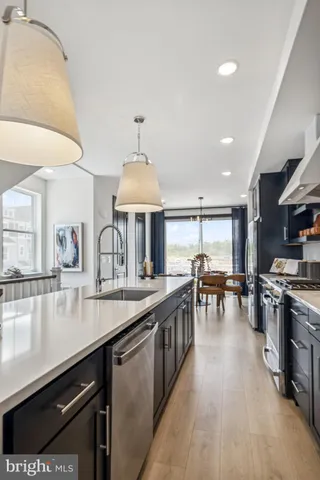 a kitchen with stainless steel appliances granite countertop a sink a stove and a wooden floors