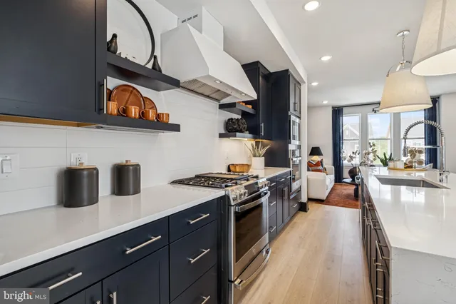 a kitchen with stainless steel appliances granite countertop a sink a stove and a wooden floors