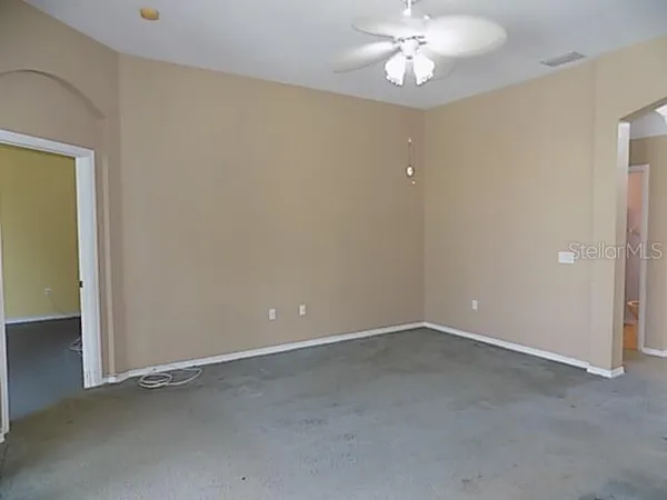 an empty room with a chandelier fan and a bathroom