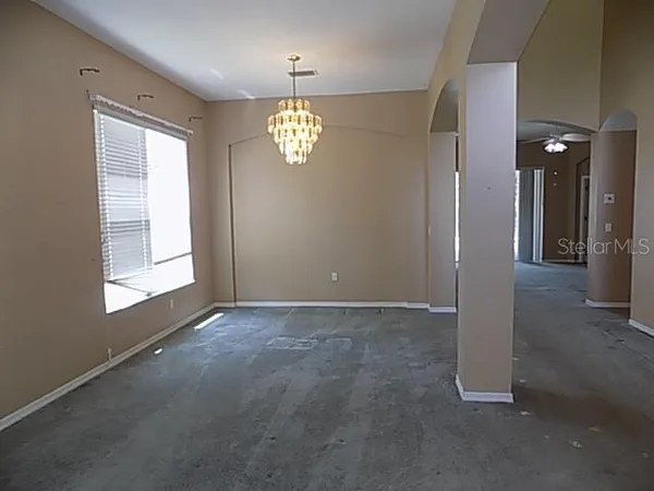 an empty room with a windows and chandelier