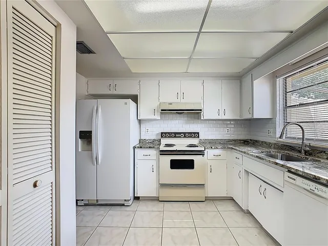 a kitchen with stainless steel appliances granite countertop a stove a sink and white cabinets