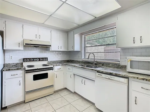 a kitchen with stainless steel appliances granite countertop a stove a sink and white cabinets