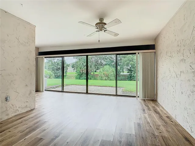 a view of an empty room with a window and wooden floor
