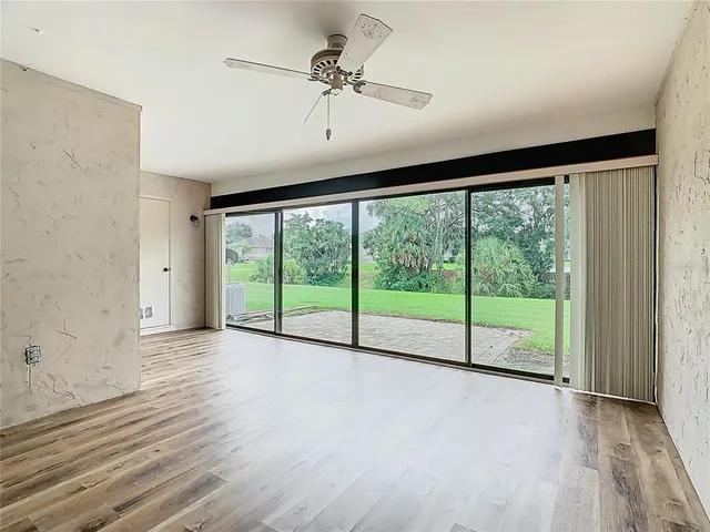 a view of a livingroom with a chandelier fan and windows