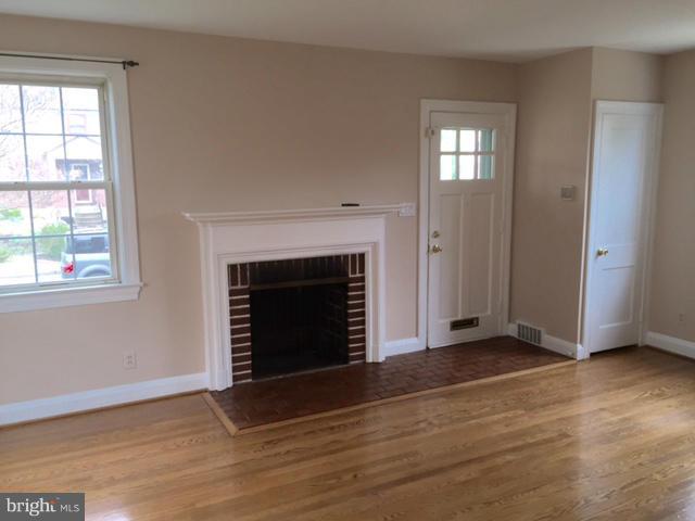 3014 Dunmurry Road Baltimore, MD 21222 - Photo 5 of 24 an empty room with wooden floor fireplace and windows