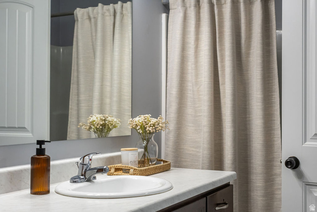2483 South 1296th Street West Logan, UT 84321 - Photo 2 of 45 Bathroom vanity featuring a white oval sink with chrome faucet, light-toned countertop, and dark wood-finish cabinetry