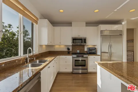 a kitchen with cabinets stainless steel appliances and a counter space