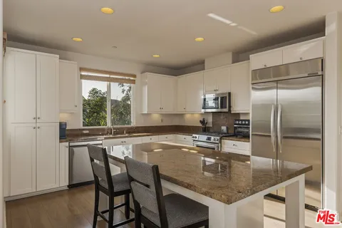 a kitchen with stainless steel appliances granite countertop a refrigerator and a stove top oven