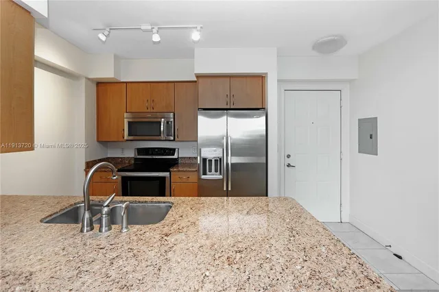 a kitchen with granite countertop a refrigerator and a sink