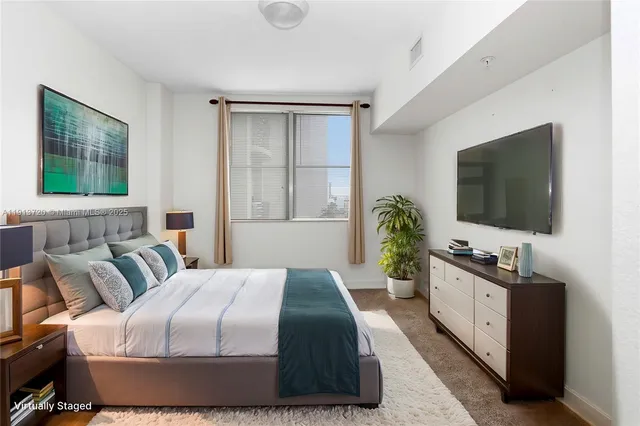 a bedroom with a bed and a flat tv screen on dresser