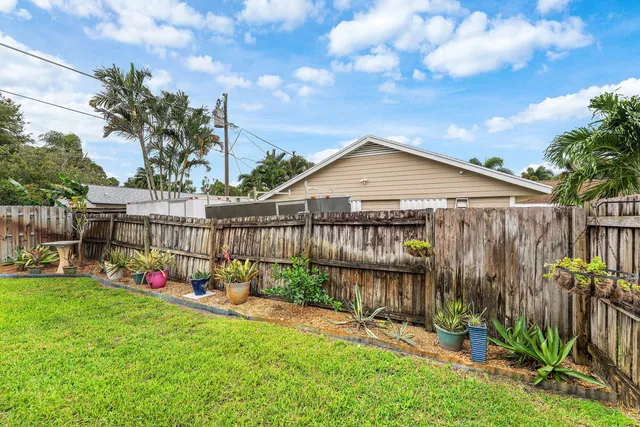 a view of backyard with green space and wooden fence